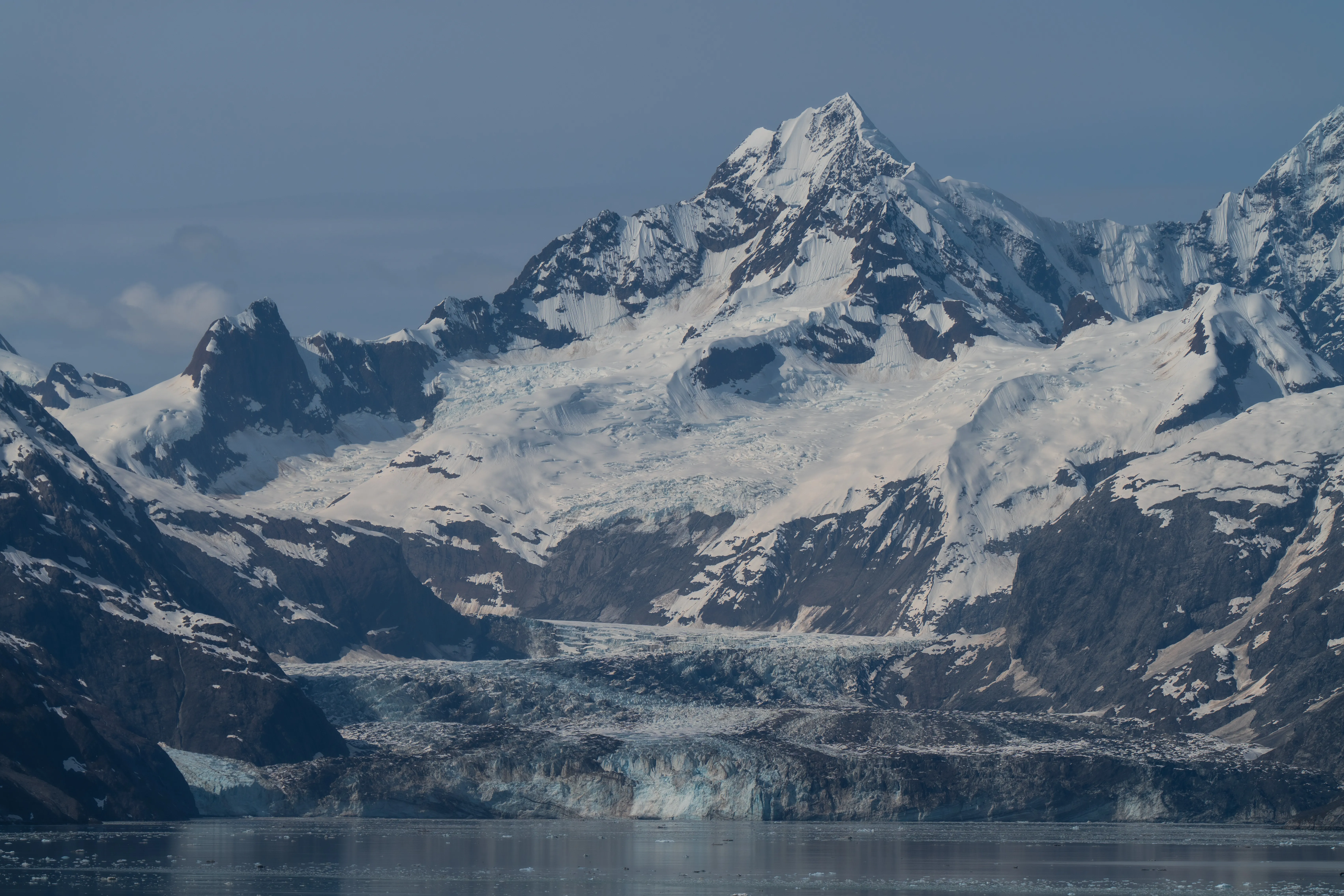 A snow-capped peak rising above a tidewater glacier that spills down to the sea